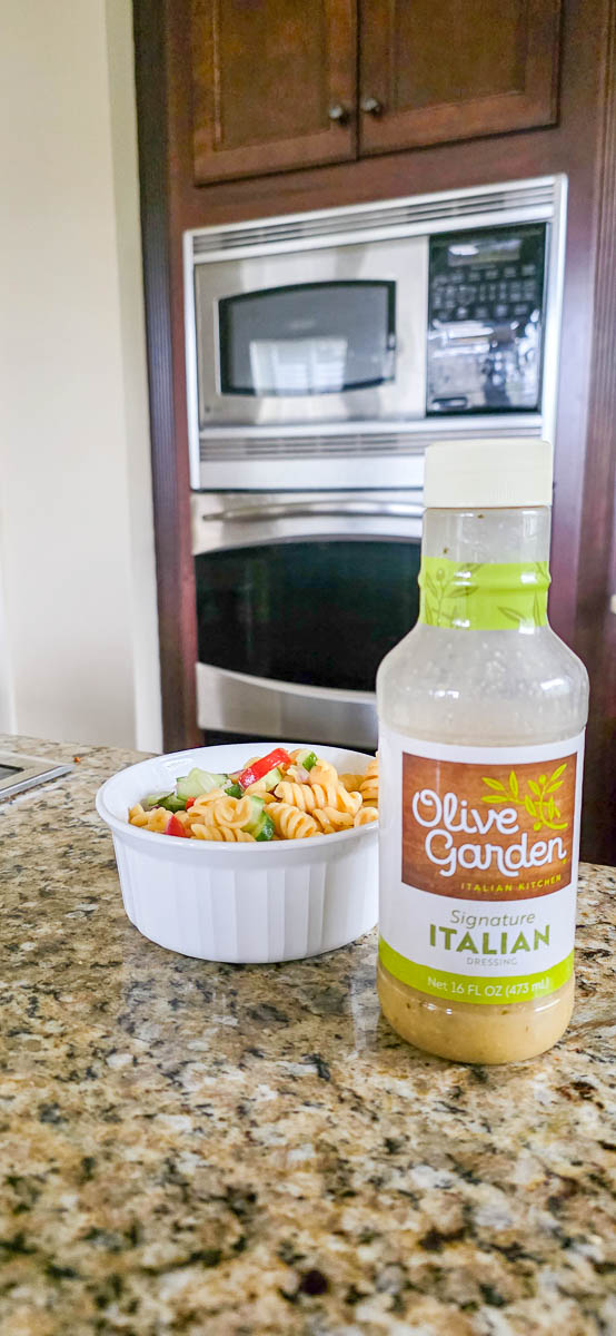 Bowl of Pasta Salad Sitting on Counter with Bottle of Olive Garden Italian Dressing