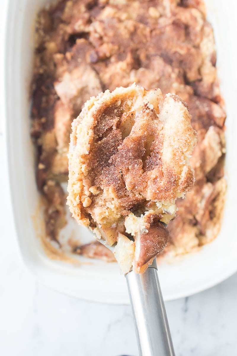 Peach Cobbler Being Scooped Out of a Glass Baking Dish