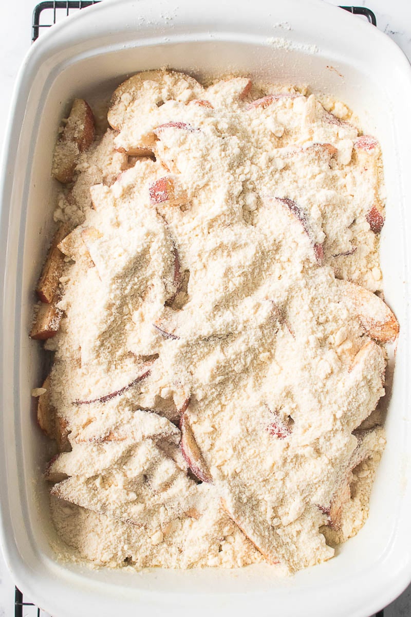 Crumble Topping Added to Apples in Glass Baking Dish