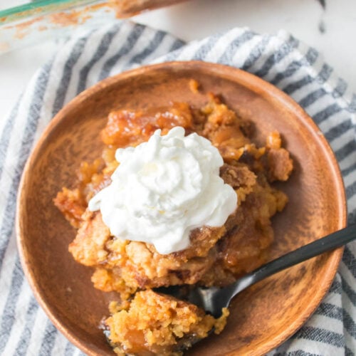 Apple Dump Cake Topped with Whipped Cream and Serving on Brown Plate