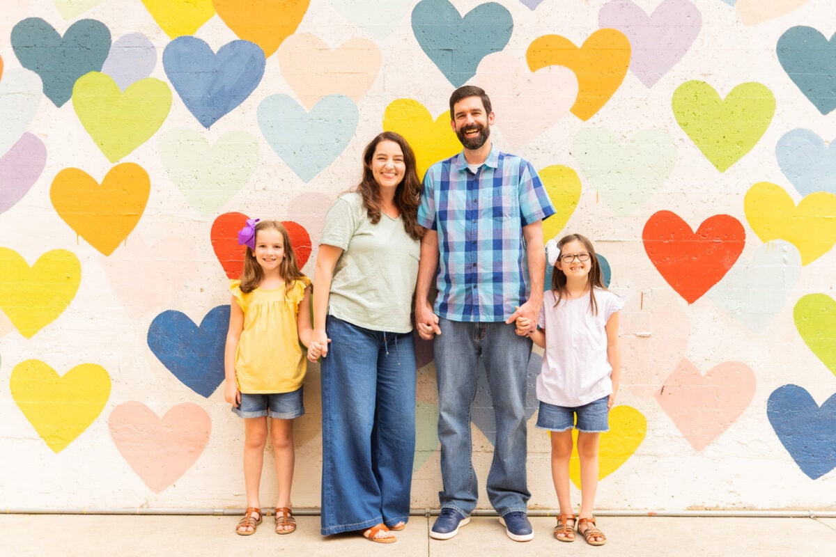Family Posing for Photo in Front of Wall of Hearts