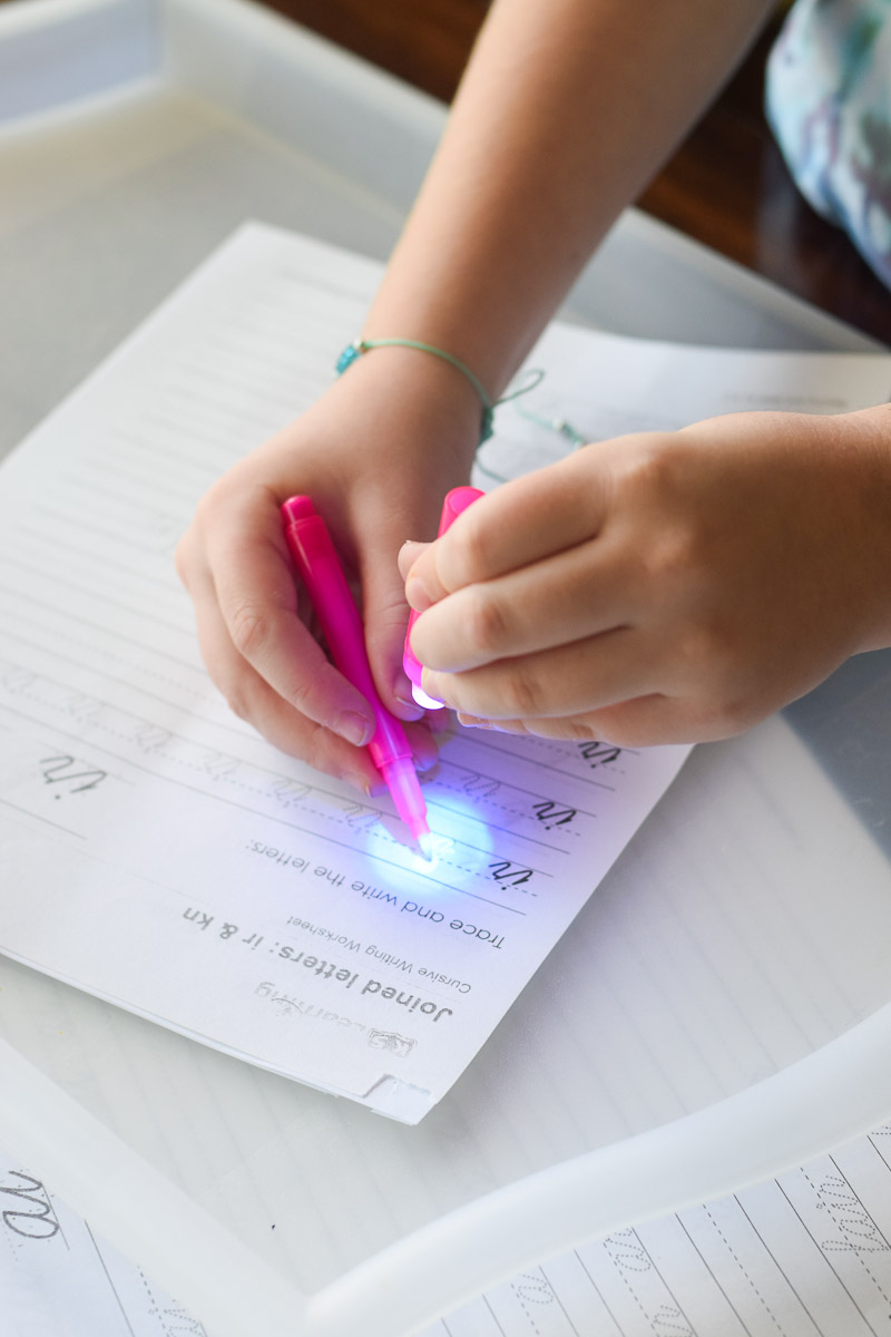 Little Girl Writing with Invisible Ink Pen that Has a Light on Top of It