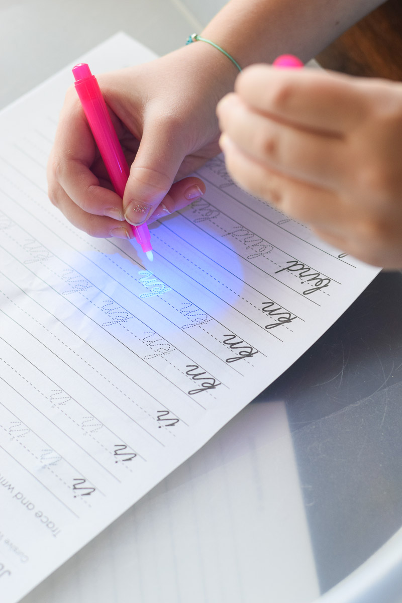 Little Girl Writing with Invisible Ink Pen that Has a Light on Top of It