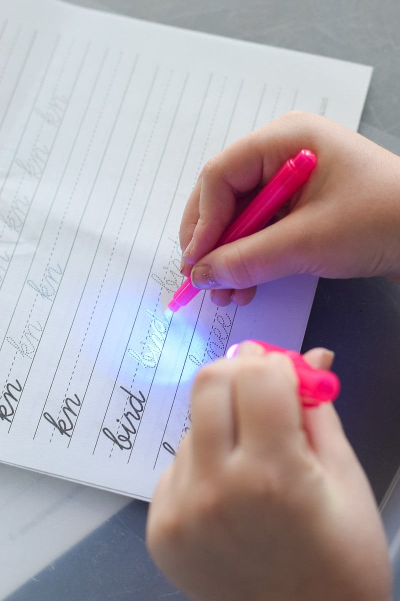 Little Girl Writing with Invisible Ink Pen that Has a Light on Top of It