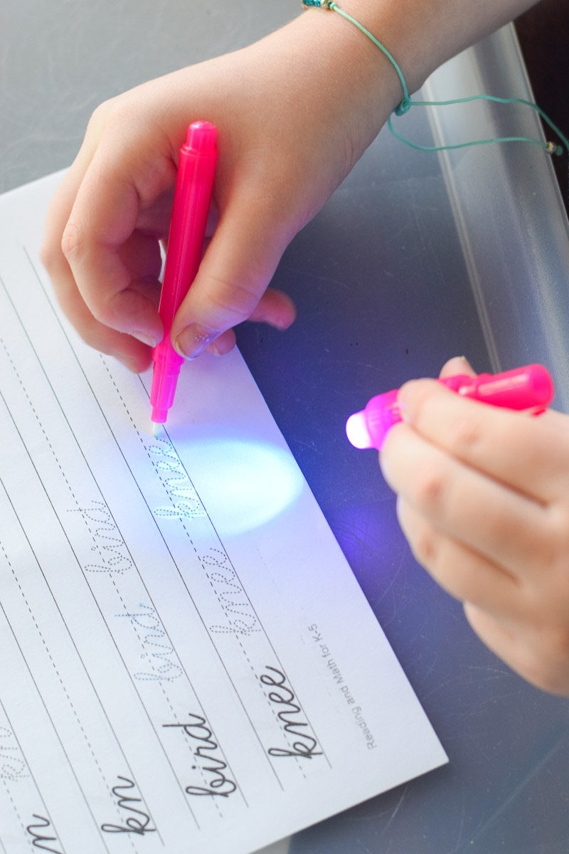 Little Girl Writing with Invisible Ink Pen that Has a Light on Top of It